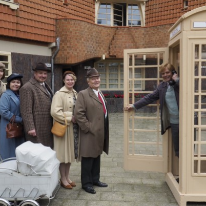 Foto van mensen in de rij bij een ouderwetse telefooncel.