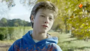 Portret van een jongen die buiten staat in de natuur.