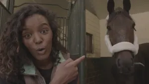 Foto van presentator, je ziet haar hoofd en hand, haar hand wijst naar het hoofd van een paard in revalidatie.
