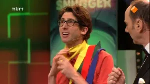 Foto van man in de studio van Snugger met een vrolijk gekleurde blouse aan, rechts van hem zie je nog wat van de presentator.