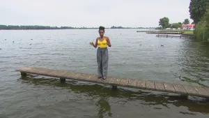 Foto van presentator die staat op een smalle kleine aanlegsteiger in groot water in de natuur.