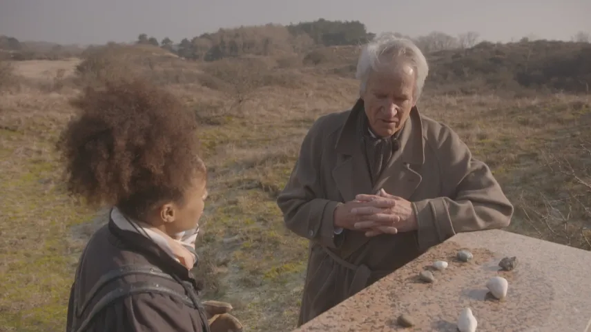 Foto van man en vrouw die in duingebied staan bij aantal steentjes die ergens op liggen.