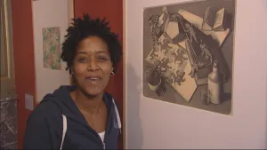 Foto van presentator die staat in een museum met een tekening van Escher aan de muur.