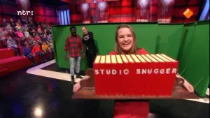 Foto van de studio van Snugger, vrouw die een rij namaakboeken draagt met erop de tekst "studio snugger".