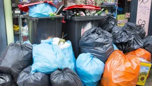 Foto van boel vuilniszakken en plastic bakken bij elkaar met rotzooi, afval, erin.