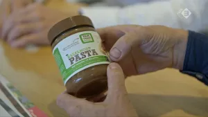 Foto van twee handen die een pot hazelnootpasta vasthouden.