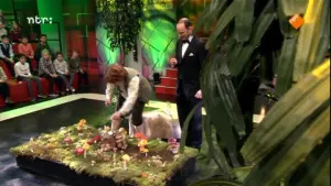 Foto van de studio van Snugger waarin de presentator en een vrouw staan bij een tafel met paddenstoelen erop.