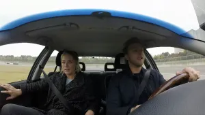 Foto van man en vrouw die rijden in een auto, foto genomen door de voorruit heen.