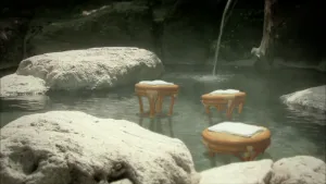 Soort ronde krukjes die staan in een warmwaterbron met grote stenen, klein watervalletje komt uit in die plas.