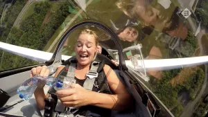 Foto van presentator die zit in een klein stuntvliegtuig die over de kop gaat.