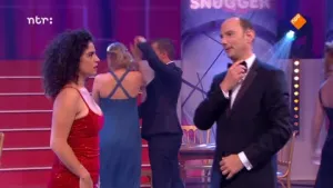 Foto van de presentator van Snugger in de studio, bij hem staat een vrouw, achter hen staan nog wat meer mensen.