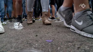 Foto van boel voeten en benen van mensen/kinderen die buiten staan op de grond.