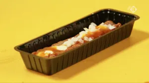 Foto van een frikandel speciaal in langwerpig plastic bakje.
