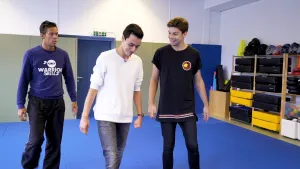 Foto van drie jongens in een gymnastiekzaal die met elkaar praten.