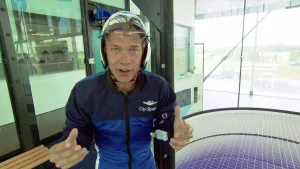 Foto van man met beschermende kleding aan die staat in de ruimte van indoor skydiven.