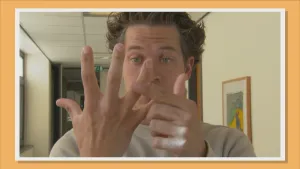 Foto van presentator die zijn hand laat zien en er één en ander over vertelt.