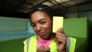 Foto van presentator in werkkleding die een stuk schuimplastic laat zien.