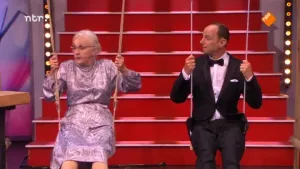 Foto van de presentator van Snugger en een oudere vrouw die elk op een schommel zitten in de studio.