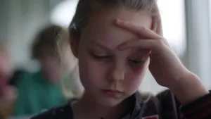 Foto van jong meisje in de klas, portret, ze ziet er moe en overspannen uit.