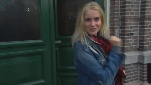 Foto van zangeres, vrouw, die buiten staat voor de ingang van een pand.