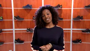 Foto van presentator met op de achtergrond een rek met schoenen erin, schoenenwinkel.