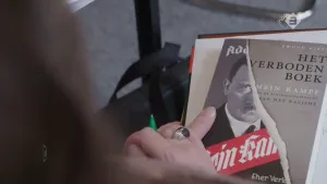 Foto van twee handen die het boek vasthouden van Mein Kampf geschreven door Hitler.