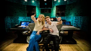 Foto van Ilse de Lange en een jongetje die samen zitten in een grote muziekstudio.