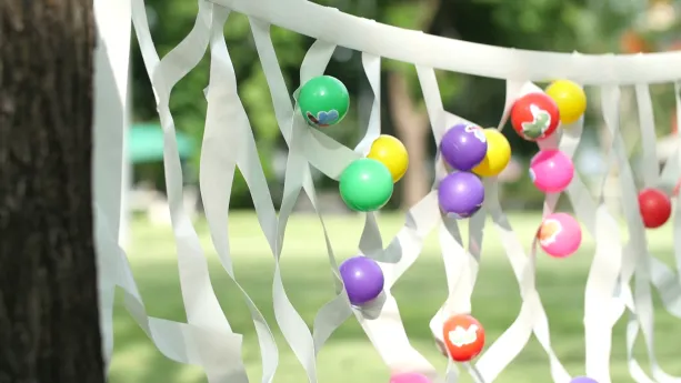 Foto van soort web gemaakt van wit plakband en balletjes van allerlei kleuren erop geplakt.