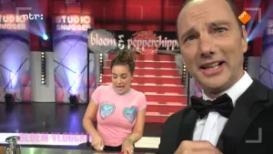 Foto van de presentator van Snugger in de studio, erachter staat nog een vrouw.