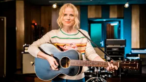 Foto van Ilse de Lange die staat en speelt op een gitaar.