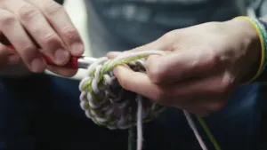 Foto van twee handen, van dichtbij genomen, die aan het haken zijn.