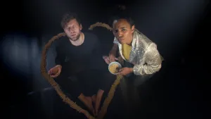 Foto van man en vrouw die in het donker zitten, ze houden schaaltjes met sojabonen erin vast.