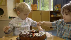 Foto van twee jonge jongetjes aan tafel bij een versierde chocoladetaart.