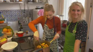 Foto van presentator bij vrouw in de keuken die eten kookt, Estée Strooker.