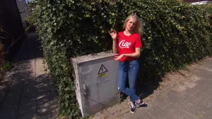 Foto van presentator die staat op de stoep bij een elektriciteitskastje.