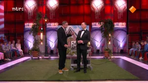 Foto van de studio van Snugger waarop het podium twee mannen staan bij een tafel met een bandrecorder erop.