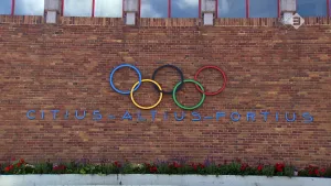 Foto van muur van gebouw waarop de 5 Olympische ringen en eronder de tekst "citius-altius-fortius".