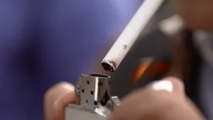 Foto, van dichtbij genomen, van een aansteker die een sigaret aansteekt.