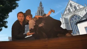 foto van Marten en Oopjen, man en vrouw bijzonder gekleed, op de achtergrond zie je een grote kerk met hoge toren.