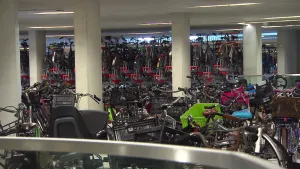 Foto van grote indoor fietsenstalling (van Utrecht C.S.) met pilaren en vele fietsen die er staan.