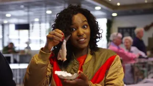 Foto van presentator die een nieuwe haring vasthoudt om zo op te eten.