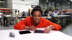 Foto van presentator die aan tafel zit in een fabriekszaal