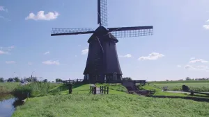 Foto van een molen op een grasdijk met smal weggetje in het boerenland.