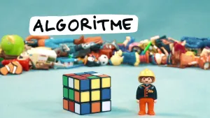 Foto van de Rubiks kubus, erbij staat een plastic (Playmobile) poppetje, op de achtergrond allerlei kleine speelgoedjes.