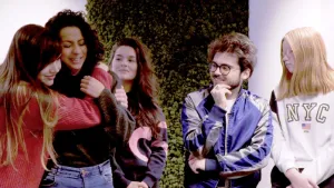 Foto van aantal meisjes en een jongen die buiten staan bij een muur met klimop.