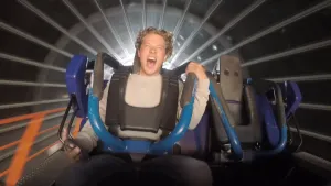 Foto van een jongen die in een achtbaan zit in een ronde tunnel, hij houdt zich goed vast en roept van plezier.