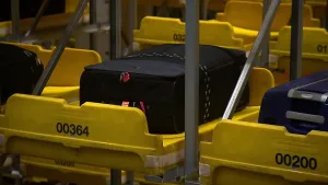 Foto van aantal gele kofferrobots bij elkaar, in elke kofferrobot ligt een koffer/tas.