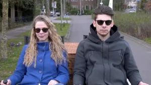 Foto van man en vrouw die op een soort dubbele fiets fietsen over een straat.