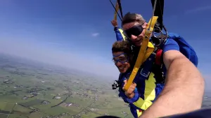 Foto van twee parachutisten aan één parachute van dichtbij genomen, springen uit een vliegtuig op vier kilometer hoogte.