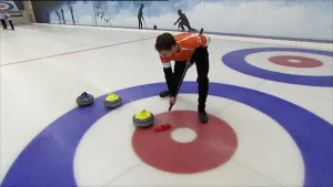 Foto van jongen die aan het curlen is, stenen schuiven over het ijs, indoor ijsbaan.